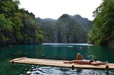 a woman laying on top of a wooden raft in the middle of a body of water