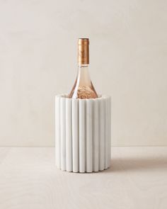 a bottle of wine sitting in a white vase