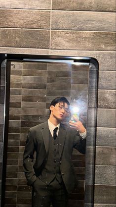 a man in a suit taking a selfie with his cell phone while standing in front of a mirror