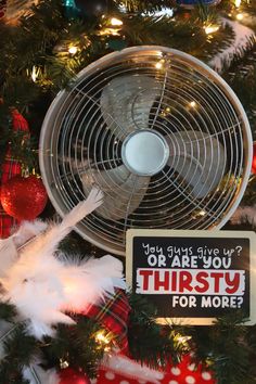 a fan sitting on top of a christmas tree next to a sign that says, you always give up or are you thirsty for more?