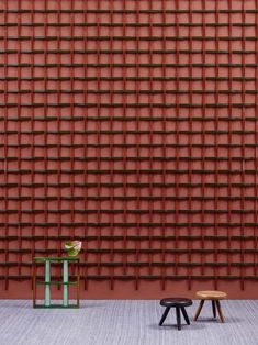 two small stools in front of a red wall