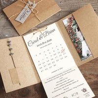 wedding stationery and programs are laid out on a wooden table for guests to sign