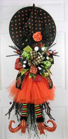 a door hanger decorated with an orange and black dress, hat, and umbrella