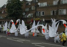 some people are walking down the street with white dresses and orange beaks in their hands