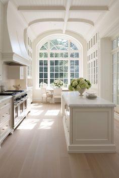 a large kitchen with white cabinets and an arched window