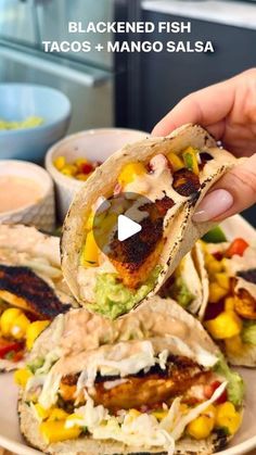 a person is holding up a taco filled with chicken and avocado salsa