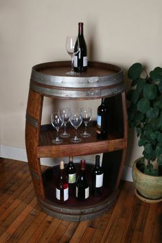 wine glasses and bottles are sitting on a wooden barrel shelf next to a potted plant