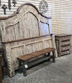 an old wooden bed frame and bench in front of a wall with clocks on it