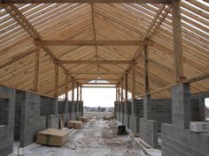 the inside of a building under construction with wooden roof and walls covered in cement blocks