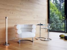 a white chair sitting next to a lamp on top of a hard wood floor