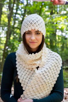 a woman wearing a white crochet hat and scarf with her hands on her hips