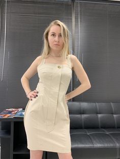 a woman standing in front of a couch with her hands on her hips and looking at the camera