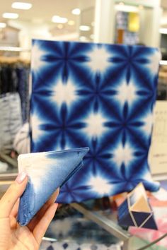 a hand holding a blue and white object in front of some other items on display