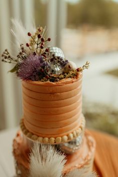 a three tiered cake decorated with feathers and flowers