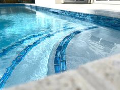 an empty swimming pool with blue tiles on the side and water flowing down it's sides