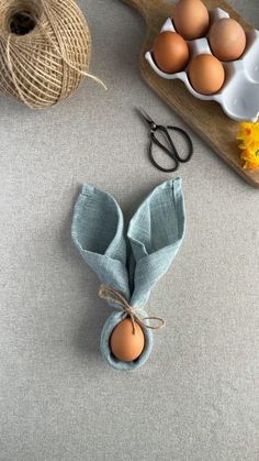 some eggs are sitting on a table next to a pair of scissors and twine