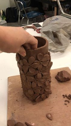 a person is making a vase out of chocolate chips on a wooden board with other items nearby