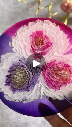 a hand holding a purple and white plate with flowers on it