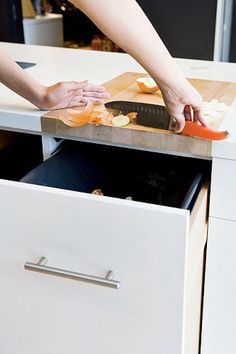 a person cutting up food on top of a kitchen counter next to an open drawer