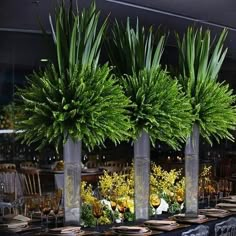 the table is set with tall vases filled with flowers and greenery