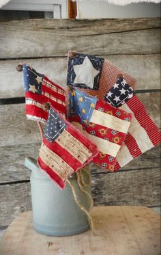 an old bucket filled with american flags on top of a wooden table