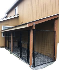 an outdoor area with a fenced in dog kennel on the side of a house