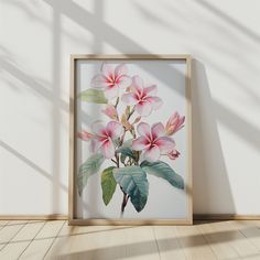 an art print with pink flowers in a wooden frame on the floor next to a white wall