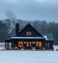 a black house in the middle of a snowy field