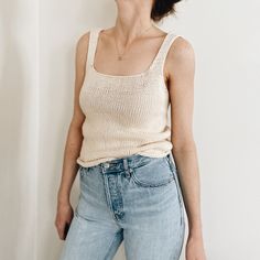 a woman standing in front of a white wall with her hands on her hips and smiling