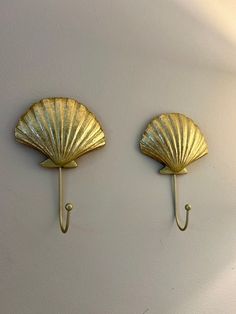 two gold scallop hooks on the wall, one is holding an umbrella and the other has a hook