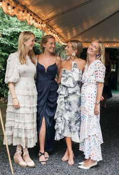 three women standing next to each other under a tent