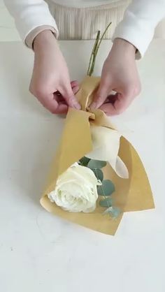 a woman is making a flower arrangement out of paper and wrapping it in brown paper