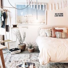 a bed sitting in a bedroom next to a window with clothes hanging on the wall