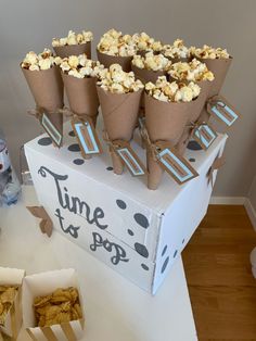 popcorn cones are stacked on top of a box with brown paper wrappers around them