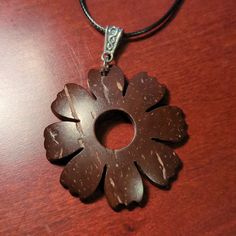 a brown flower shaped pendant on a leather cord