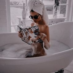 a woman sitting in a bathtub reading a magazine