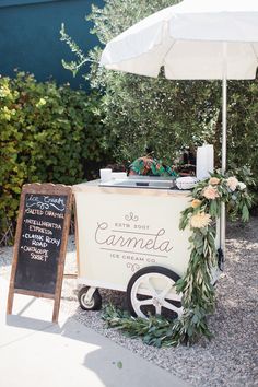 an ice cream cart is decorated with flowers and greenery for a bridal event