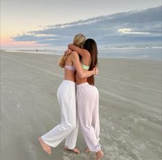 two women hugging each other on the beach