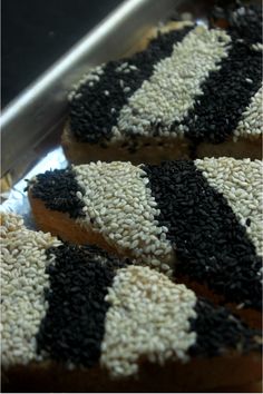 two donuts with black and white sprinkles are on a metal tray