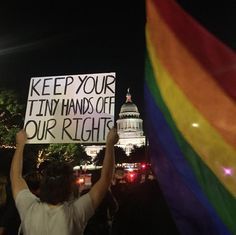 a protester holds up a sign that reads keep your tiny hands off our rights