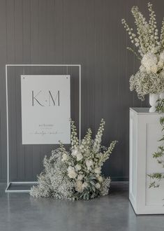 two vases with flowers are sitting on the floor next to a sign that says k m