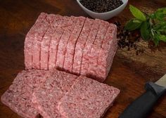 raw ground beef is cut into cubes and placed next to a knife on a cutting board