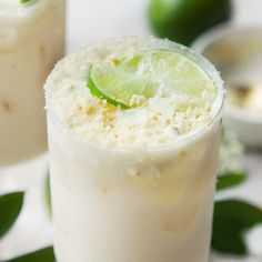 two glasses filled with drinks and garnished with limes