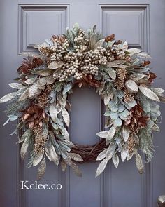 a wreath with leaves and berries hanging from the front door, on a gray door