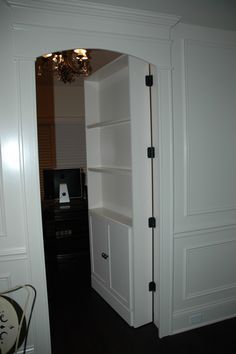 an open door leading into a room with white walls and black carpeted flooring