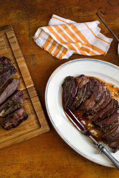 a plate with steak and sauce on it next to a cutting board, fork and knife