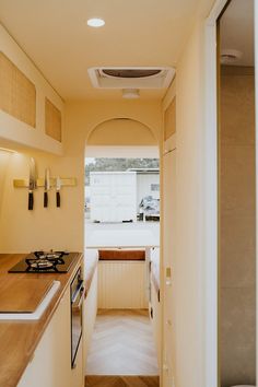 a narrow hallway leading to a kitchen with an oven and stove top on the counter