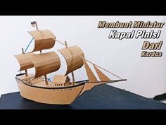 a wooden model of a boat on top of a black surface with text that reads, membat milhatur kapai pinisi