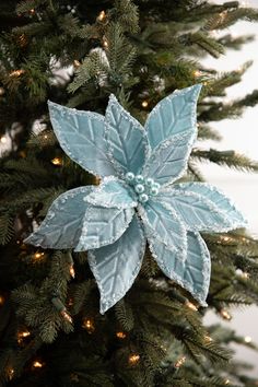 a blue poinsettia ornament hanging from a christmas tree