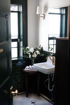 a white sink sitting next to a window in a bathroom on top of a tiled floor